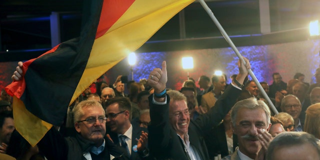 Supporters of the nationalist Alternative for Germany AfD celebrate after the state election in the German state of Hesse in Wiesbaden, western Germany, Sunday, Oct. 28, 2018. Exit polls show Chancellor Angela Merkel’s party leading with a significant drop in support for both her conservatives and their center-left partners in the national government. (Frank Rumpenhorst/dpa via AP)
