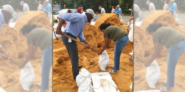 Tallahassee Mayor and Democratic gubernatorial candidate, Andrew Gillum, left, helps Eboni Sipling fill up sandbags in Tallahassee, Fla., Monday, Oct. 8, 2018.