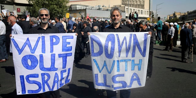 Two Iranian worshippers hold up anti-American and anti-Israeli placards, in a rally to condemn Saturday's terror attack in Ahvaz, after Friday prayers in Tehran, Iran, Friday, Sept. 28, 2018.