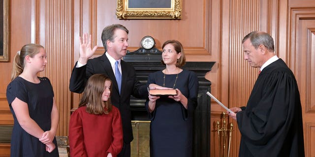 Chief Justice John Roberts, right, administers the Constitutional Oath to Judge Brett Kavanaugh in the Justices' Conference Room of the Supreme Court Building. Ashley Kavanaugh holds the Bible. In the foreground are their daughters, Margaret, left, and Liza. (Fred Schilling/Collection of the Supreme Court of the United States via AP)