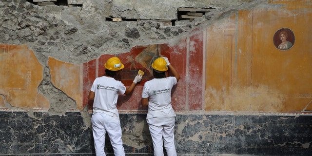 The restorers are working on a fresco recently discovered in the Regio V district of Pompeii.