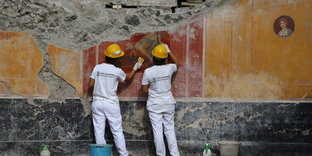 Restorers work on a recently-discovered fresco in the Regio V area of Pompeii.