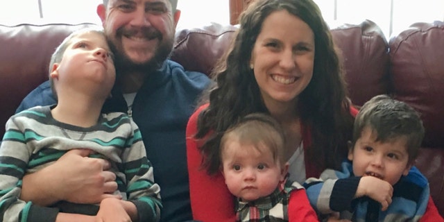 In this Dec. 10, 2017 photo provided by the family, Jon and Kari Kilquist sit with their children, from left, Will, who was born with a list of mysterious symptoms, Emmy and Owen at their home in Murphysboro, Ill.