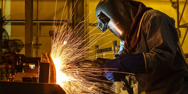 Worker, welding in a car factory with sparks, manufacturing, industry