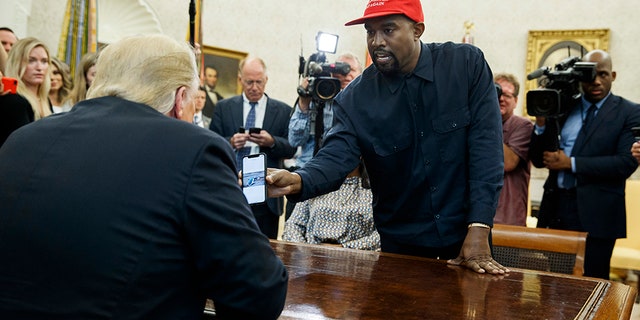 Rapper Kanye West shows President Trump a photograph of a hydrogen plane during a meeting in the Oval Office of the White House, Thursday, Oct. 11, 2018.