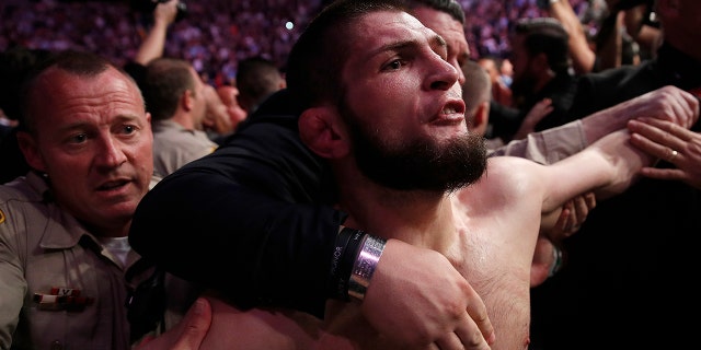 Khabib Nurmagomedov is held back outside of the cage after fighting Conor McGregor in a lightweight title mixed martial arts bout at UFC 229.