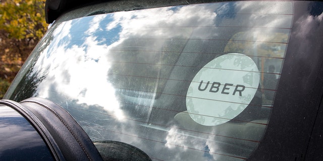 Rear window of a black Uber car with the white Uber sticker on the glass.