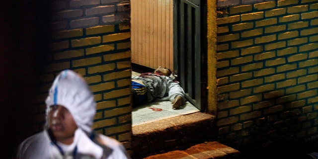 A body is stretched out at the door of a bar in the community of Comayaguela, Honduras, on Friday. At least eight people were killed and two others wounded at the bar that day, police say. (AP Photo/Fernando Antonio)