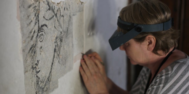 A conservator painstakingly uncovering the painting in the Bloody Tower.