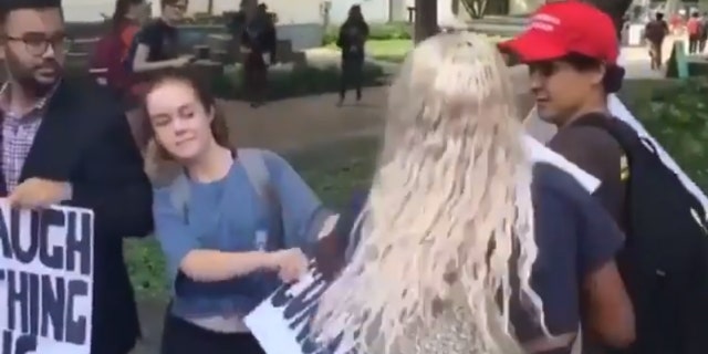 A student rips apart a pro-Kavanaugh sign from the Young Conservatives of Texas at the University of Texas, Austin on Tuesday.