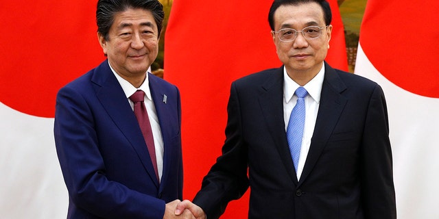 Japanese Prime Minister Shinzo Abe, left, shakes hands with Chinese Premier Li Keqiang after their joint news conference at the Great Hall of the People in Beijing, Friday, Oct. 26, 2018. (Associated Press)