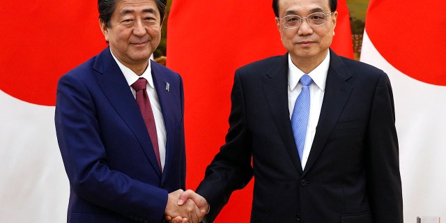 Japanese Prime Minister Shinzo Abe, left, shakes hands with Chinese Premier Li Keqiang after their joint news conference at the Great Hall of the People in Beijing, Friday, Oct. 26, 2018. (Associated Press)