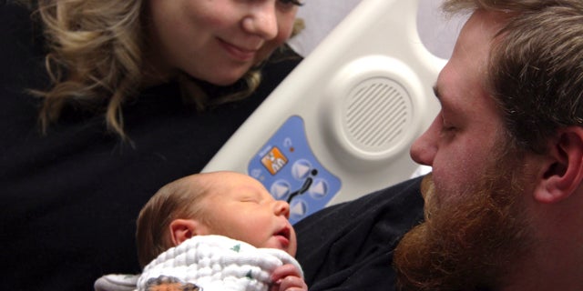 In this Tuesday, Oct. 23, 2018, photo Andrew Goette and his wife, Ashley, look at their baby, Lennon, at United Hospital in Saint Paul, Minn.