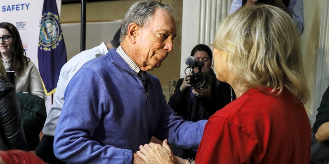 Former New York Mayor Michael Bloomberg talks to a woman who lost her daughter to gun violence after speaking at a rally at City Hall in Nashua, New Hampshire, on Saturday.