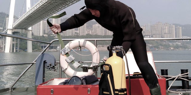 A diver prepares to conduct a search and rescue operation at the site where a bus has plunged off a bridge into the Yangtze River in Wanzhou in southwest China's Chongqing Municipality Sunday, Oct. 28, 2018