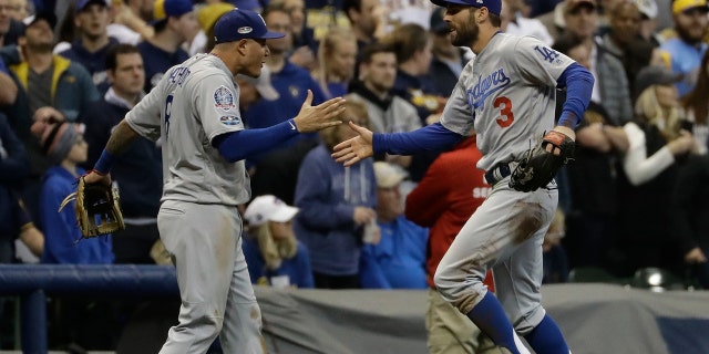 Los Angeles Dodgers' Chris Taylor is congratulated by Manny Machado after catching a ball hit by Milwaukee Brewers' Christian Yelich during the fifth inning of Game 7 of the National League Championship Series baseball game Saturday, Oct. 20, 2018, in Milwaukee. 