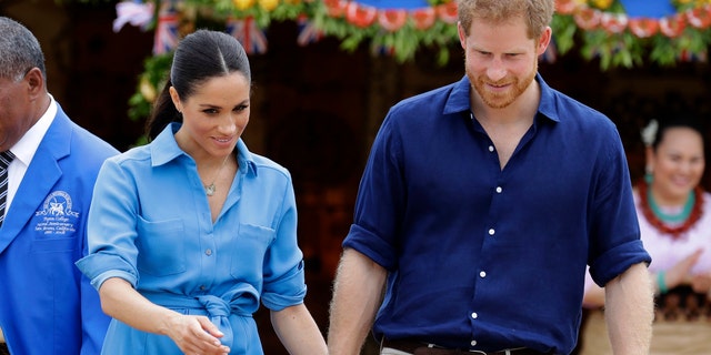 British Prince Harry and Meghan, the Duchess of Sussex, smile during a visit to Tupou College in Tonga on Friday, October 26, 2018.