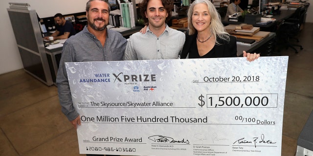 The Skysource/Skywater Alliance co-founders David Hertz, left, his wife Laura Doss-Hertz, right, and project designer Willem Swart pose for a photo with an image of a $1.5 million prize the company received Wednesday in Los Angeles.