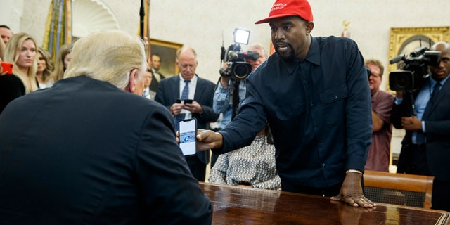 Rapper Kanye West shows President Donald Trump a photograph of a hydrogen plane during a meeting in the Oval Office of the White House, Thursday, Oct. 11, 2018, in Washington.