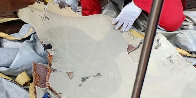 In this photo released by Indonesian Disaster Mitigation Agency (BNPB) a rescuer inspects debris believed to be from a Lion Air passenger jet that crashed off West Java on Monday, Oct. 29, 2018.