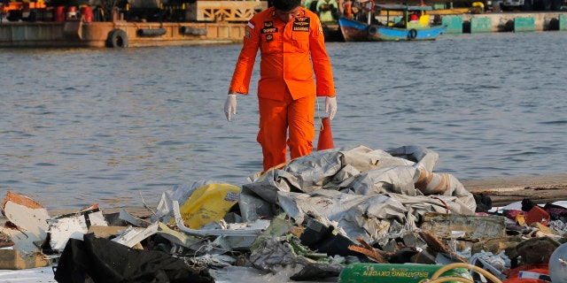 A member of Indonesian Search and Rescue Agency (BASARNAS) inspects debris recovered from near waters where a Lion Air passenger jet crashed off, at Tanjung Priok Port in Jakarta, Indonesia Monday, Oct. 29, 2018.