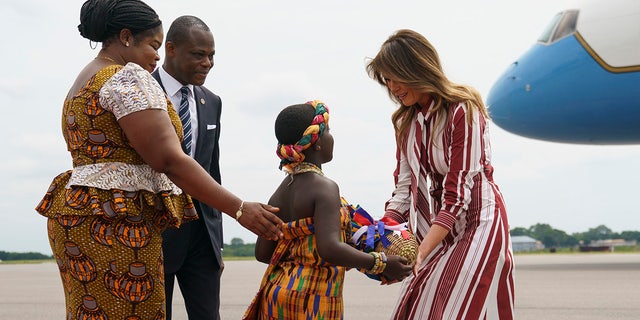 First lady Melania Trump accepts flowers from flower girl Lillian Naa Adai Sai, 8, as she receives flowers as she arrives at Kotoka International Airport in Accra, Ghana, Tuesday, Oct. 2