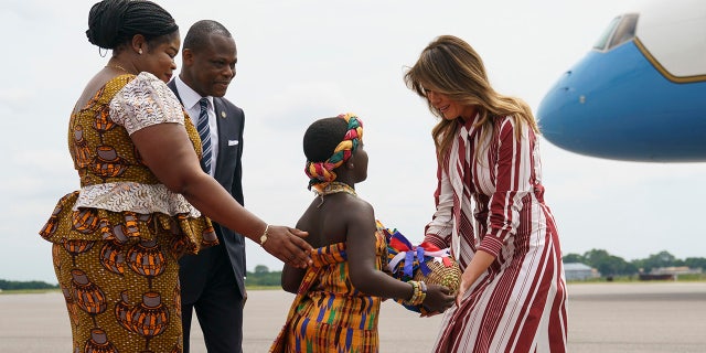 First lady Melania Trump accepts flowers from flower girl Lillian Naa Adai Sai, 8, as she receives flowers as she arrives at Kotoka International Airport in Accra, Ghana, Tuesday, Oct. 2