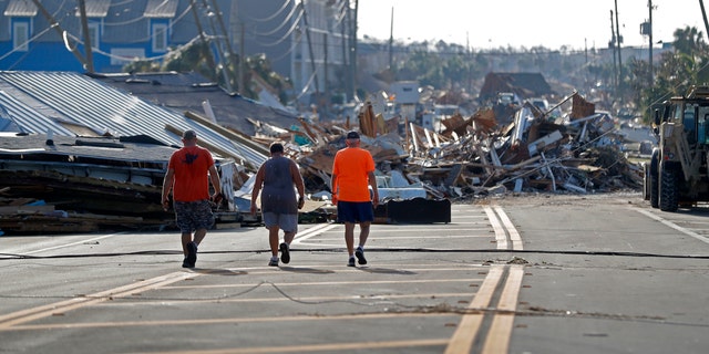 People walk amidst destruction on the main street of Mexico Beach, Fla.