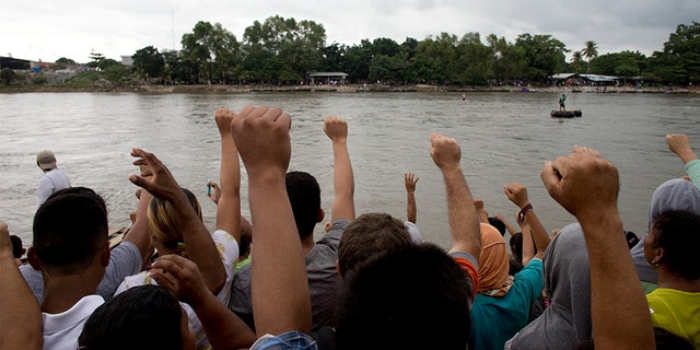 Honduran migrants sing their national anthem standing standing at the shore of the Suchiate river on the border between Guatemala and Mexico.
