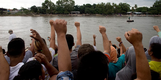 Honduran migrants sing their national anthem standing at the shore of the Suchiate river on the border between Guatemala and Mexico.