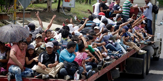 Honduran migrants who are traveling to the United States as a group, get a free ride in the back of a trailer truck flatbed, as they make their way through Teculutan, Guatemala.