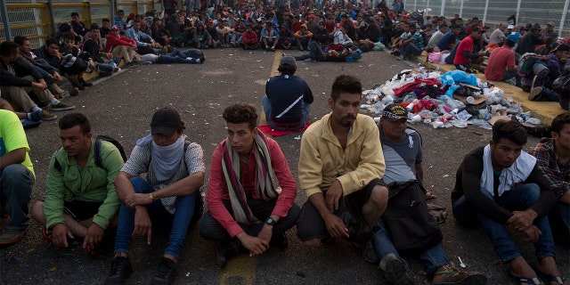 Migrants bound for the U.S.-Mexico border wait on a bridge that stretches over the Suchiate River, connecting Guatemala and Mexico, in Tecun Uman, Guatemala, early Saturday, Oct. 20, 2018. The entry into Mexico via the bridge has been closed. The migrants have moved about 30 feet back from the gate that separates them from Mexican police to establish a buffer zone. About 1,000 migrants now remain on the bridge between Guatemala and Mexico. (AP Photo/Moises Castillo)