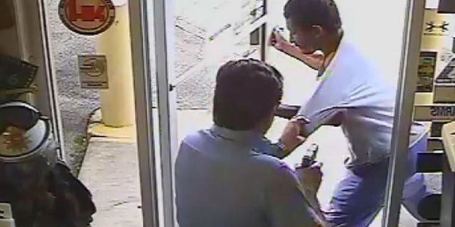 Lakeland Commissioner Michael Dunn holds a gun in his right hand while trying to keep Cristobal Lopez from carrying a hatchet out of his store on Oct. 3.