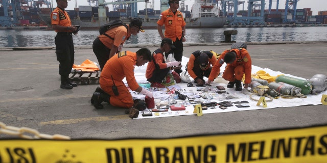 Rescuers examine personal belongings of passengers of a crashed Lion Air plane recovered from the waters near where the passenger jet is believed to have crashed, at Tanjung Priok Port in Jakarta, Indonesia, Tuesday, Oct. 30, 2018.