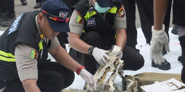 Indonesian forensic team members examine parts of airplane recovered from the area where a Lion Air plane crashed.