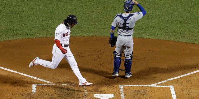 Boston Red Sox's Andrew Benintendi scores past Los Angeles Dodgers catcher Austin Barnes on a hit by J.D. Martinez during the fifth inning of Game 2 of the World Series baseball game Wednesday, Oct. 24, 2018, in Boston. (AP Photo/David J. Phillip)