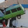 A man takes a photo of a car lifted into the air following a massive earthquake and tsunami at Talise beach in Palu, Central Sulawesi, Indonesia, Oct. 1, 2018. 