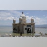A man looks at a mosque that is isolated by water after its bridge was broken due to the massive earthquake and tsunami in Palu, Central Sulawesi, Indonesia Oct. 5, 2018.
