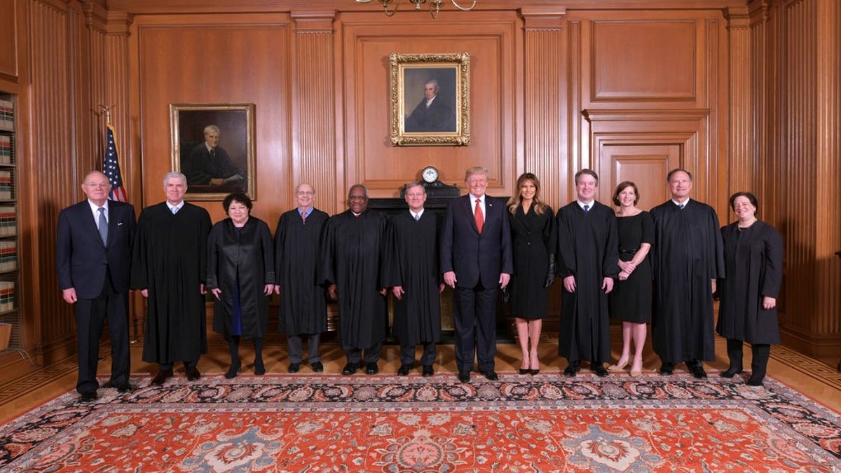 In this image provided by the Supreme Court, President Donald Trump poses for a photo with Associate Justice Brett Kavanaugh in the Justices' Conference Room before a investiture ceremony Thursday, Nov. 8, 2018, at the Supreme Court in Washington. From left are, retired Justice Anthony Kennedy, Associate Justices Neil Gorsuch, Sonia Sotomayor, Stephen Breyer, Clarence Thomas, Chief Justice John Roberts, Jr., President Donald Trump, first lady Melania Trump, Associate Justice Brett Kavanaugh, Ashley Kavanaugh, and Associate Justices Samuel Alito, Jr. and Elena Kagan.
