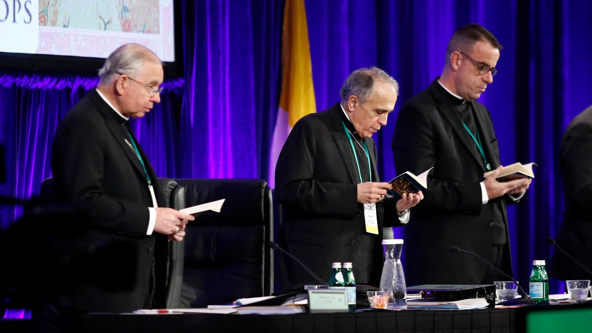 Cardinal Daniel DiNardo of the Archdiocese of Galveston-Houston, center, president of the United States Conference of Catholic Bishops, participates in a morning prayer alongside Jose Gomez, archbishop of Los Angeles and conference vice president, at left, and Rev. J. Brian Bransfield, conference general secretary, at the USCCB's annual fall meeting, Tuesday, Nov. 13, 2018, in Baltimore. (AP Photo/Patrick Semansky)