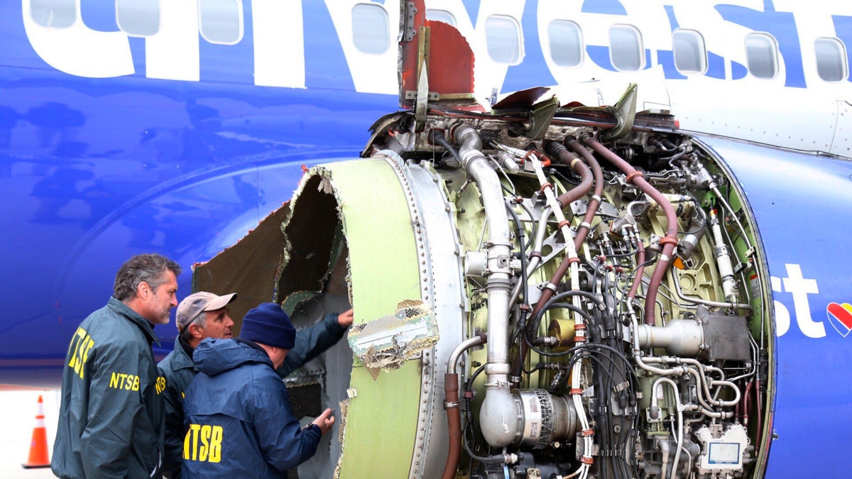 In this April 17, 2018, file photo National Transportation Safety Board investigators examine damage to the engine of the Southwest Airlines plane that made an emergency landing at Philadelphia International Airport in Philadelphia. (NTSB via AP)