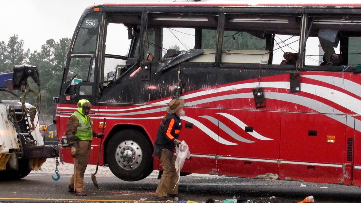 Workers clear debris from the scene of a bus crash that killed at least two people and injured dozens on Wednesday, Nov. 14, 2018, in Byhalia, Miss.