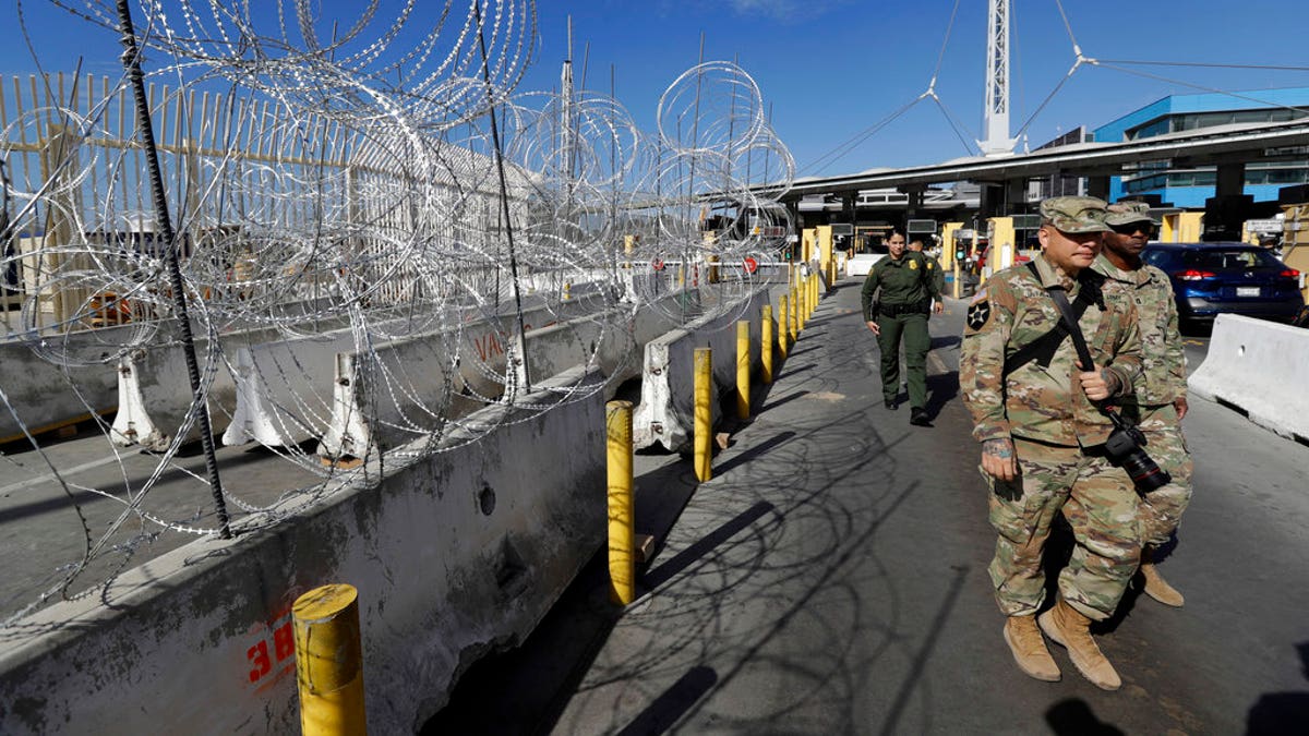 U.S. Border Patrol agents and members of the military pass concertina wire during a tour of the San Ysidro port of entry in San Diego.