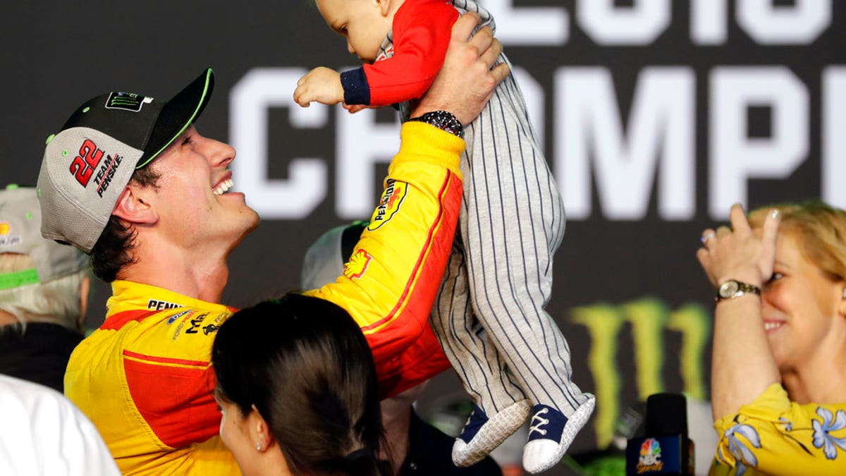 Joey Logano holds his son Hudson after winning the NASCAR Cup Series Championship auto race at the Homestead-Miami Speedway, Sunday, Nov. 18, 2018, in Homestead, Florida.