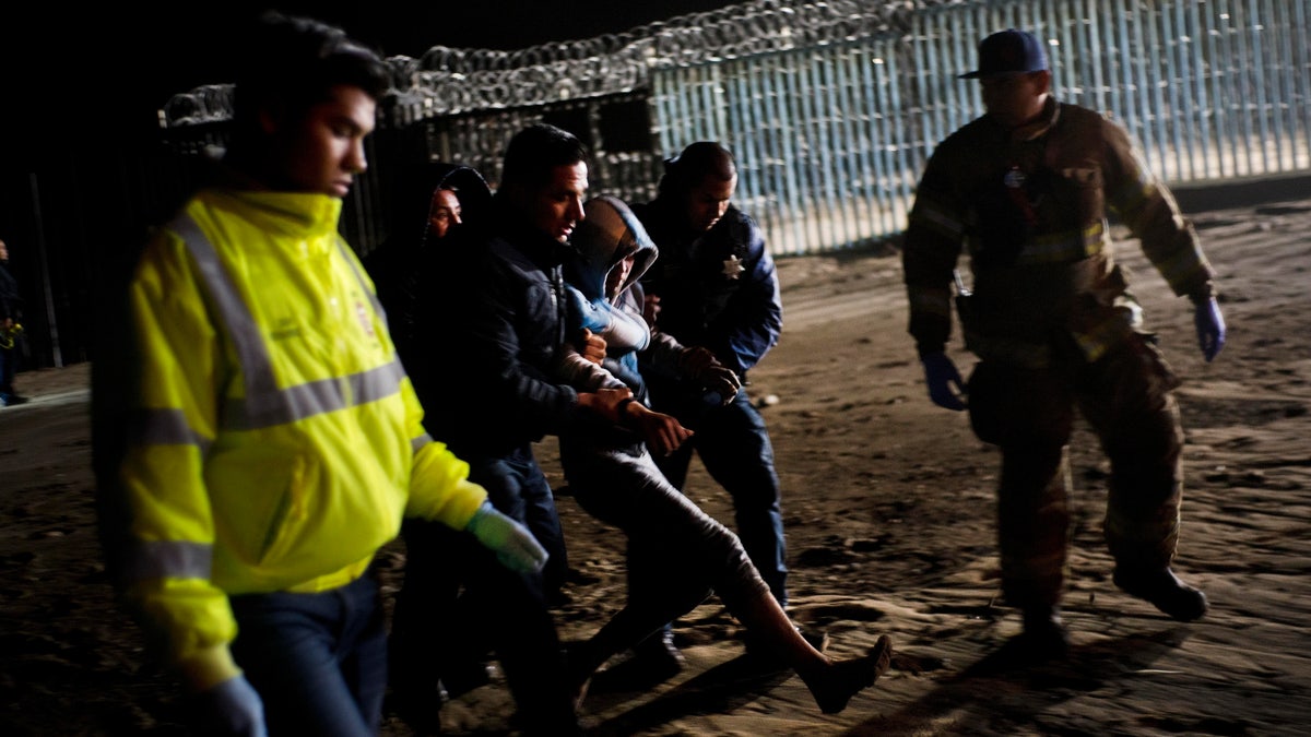 Authorities hold a Honduran migrant who was rescued after he tried to cross the US border by the sea in Tijuana beach, Mexico, Thursday, Nov. 29, 2018. (AP Photo/Ramon Espinosa)