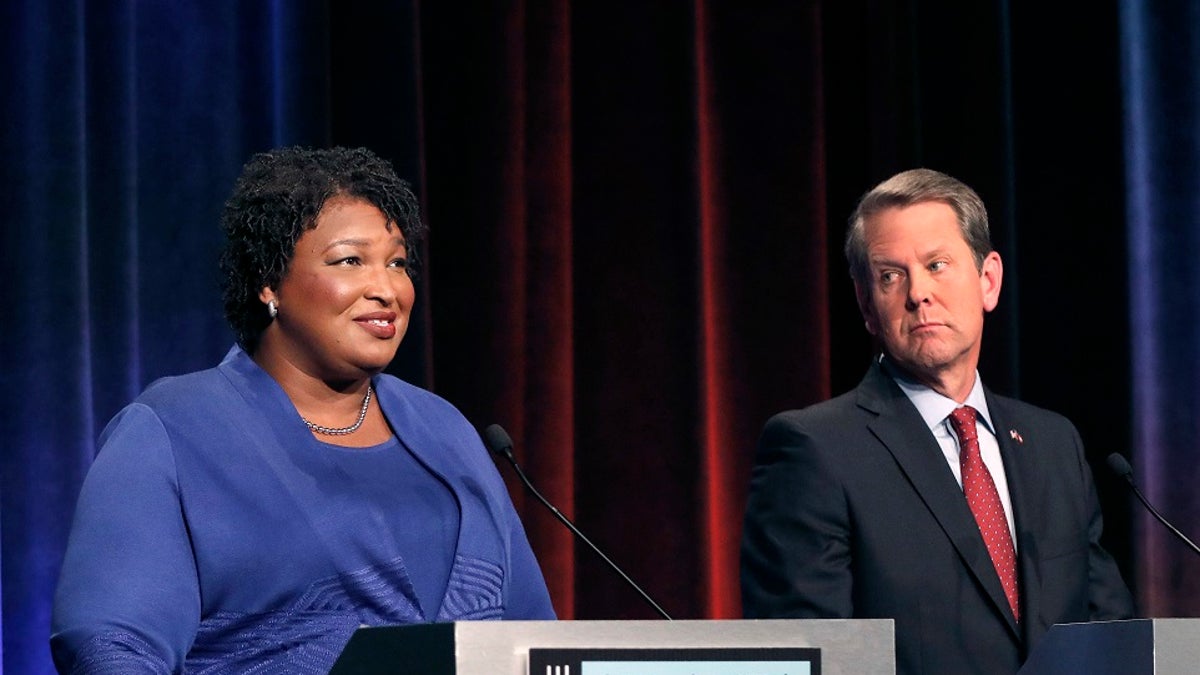 FILE - Democratic gubernatorial candidate for Georgia Stacey Abrams, left, speaks as her Republican opponent Secretary of State Brian Kemp looks on during a debate in Atlanta.