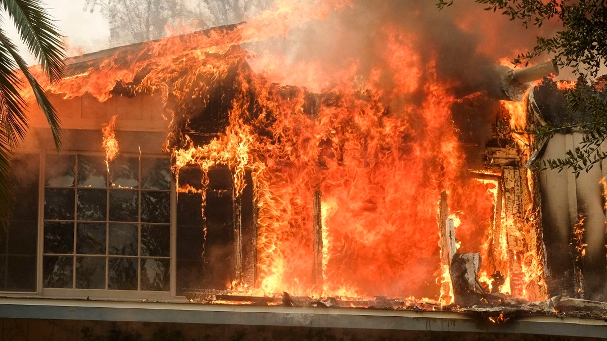The Woolsey Fire burns a home near Malibu Lake in Malibu, Calif., Friday, Nov. 9, 2018.