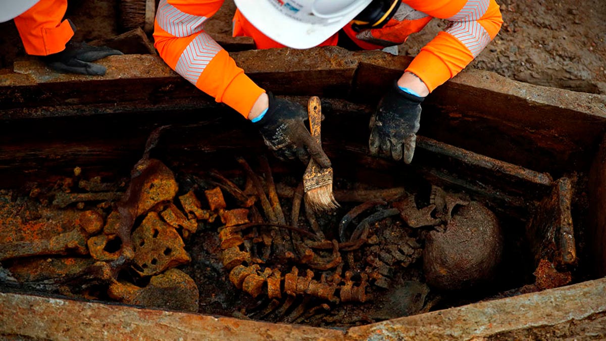 A field archaelogist uses a brush on a skeleton in an open coffin during the excavation of a late 18th to mid 19th century cemetery under St James Gardens near Euston train station in London on November 1, 2018 as part of the HS2 high-speed rail project. (Credit: ADRIAN DENNIS/AFP/Getty Images)