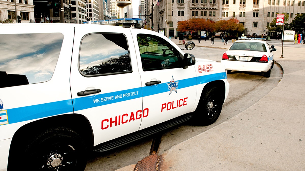 Chicago police car parked on city street as people walk by
