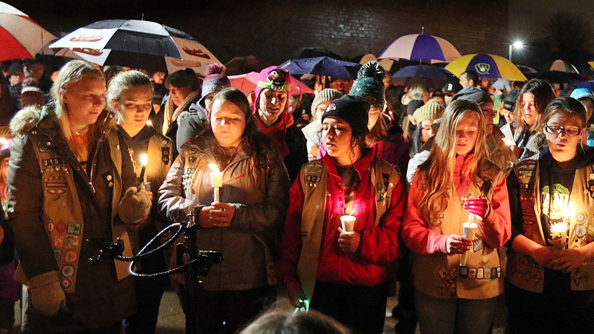 Girl Scouts sing as hundreds of community members turn out in the rain Sunday evening for a candlelight vigil at Halmstad Elementary in Chippewa Falls, Wisconsin.